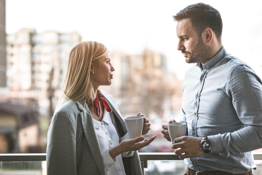 Husband and Wife having coffee on the balcony of a building.
